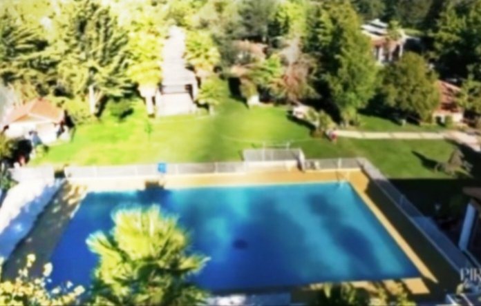 Vista aérea de la piscina principal rodeada de prado y árboles