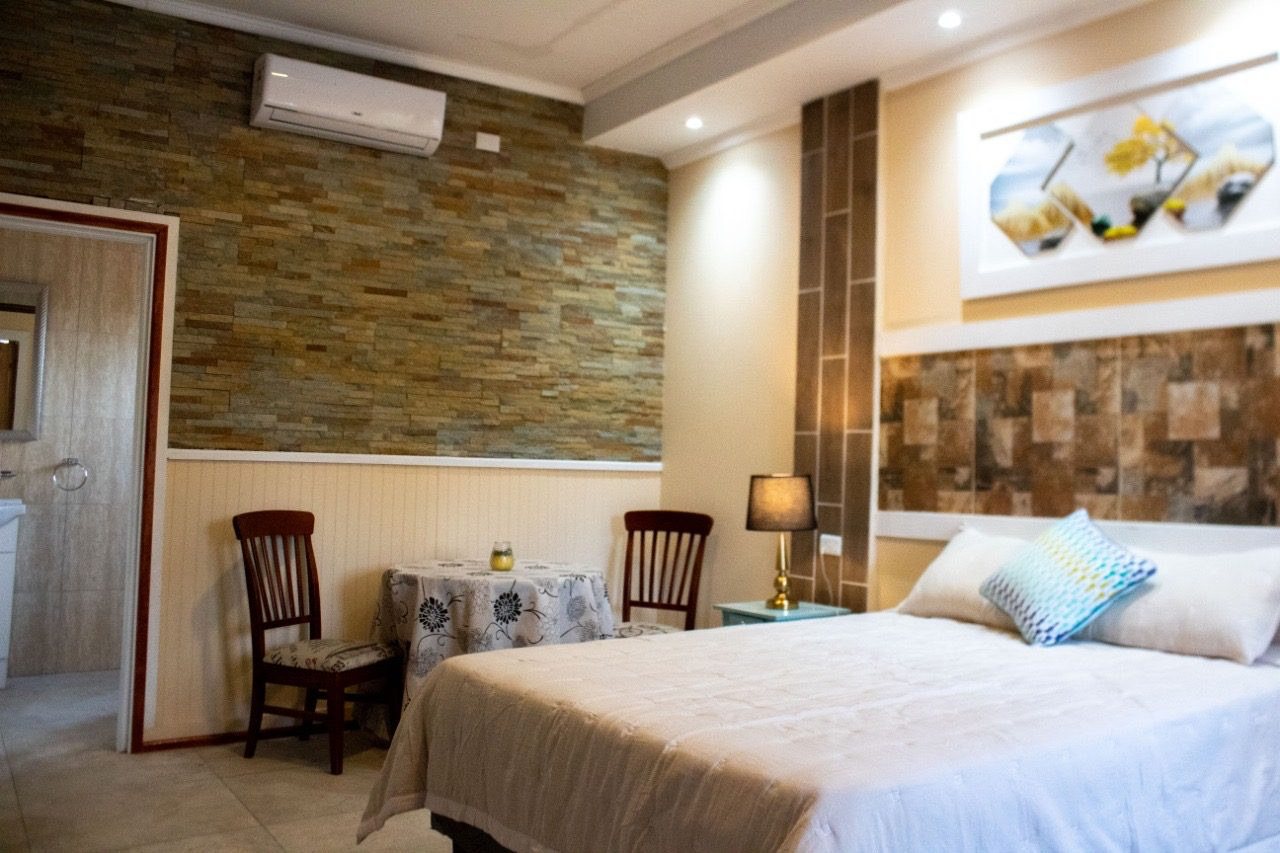 Habitación con cama matrimonial, muro de piedra y cuadro decorativo